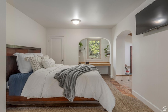 bedroom featuring baseboards and arched walkways