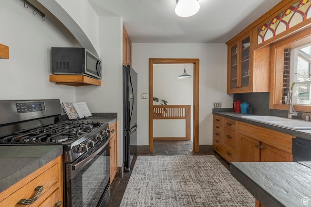 kitchen with a sink, baseboards, glass insert cabinets, brown cabinetry, and black appliances