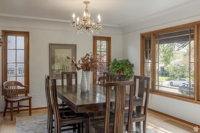 dining area featuring a notable chandelier, baseboards, crown molding, and light wood-type flooring