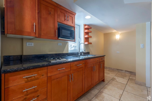 kitchen with dark stone counters, brown cabinets, black microwave, and a sink
