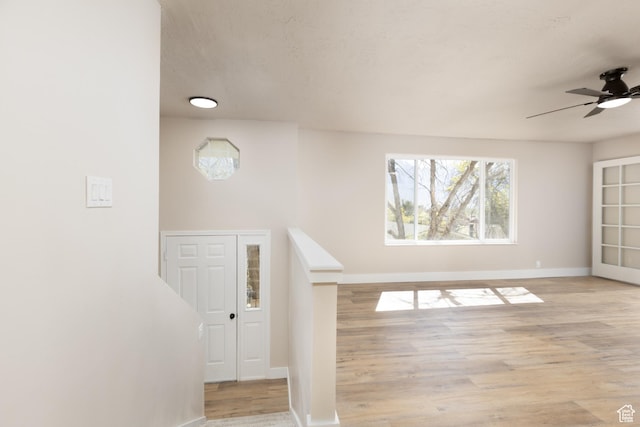 interior space with wood finished floors, a ceiling fan, and baseboards