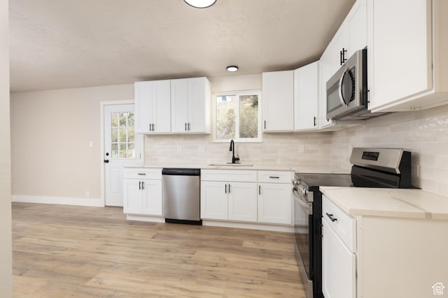 kitchen with backsplash, white cabinetry, stainless steel appliances, and a sink