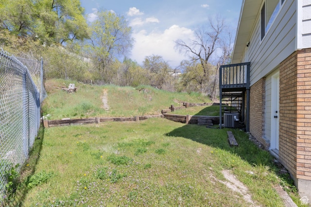 view of yard with central AC unit, stairway, and fence
