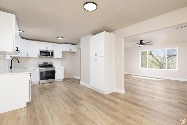 kitchen with stainless steel appliances, visible vents, a sink, baseboards, and open floor plan