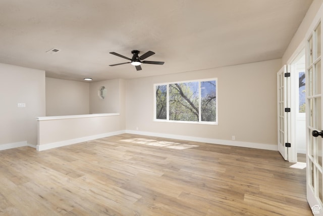 spare room with baseboards, a ceiling fan, visible vents, and light wood-style flooring