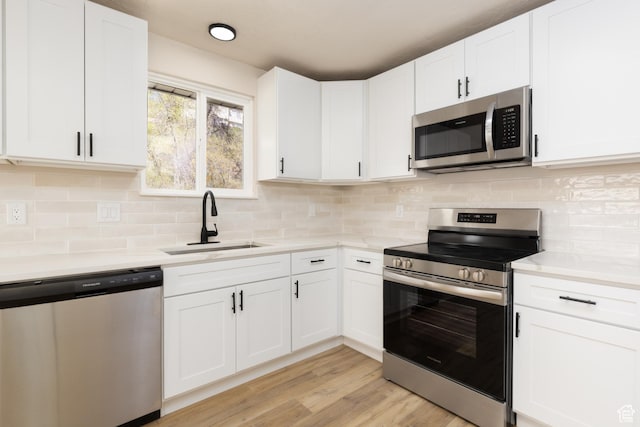 kitchen with light countertops, appliances with stainless steel finishes, white cabinetry, and a sink
