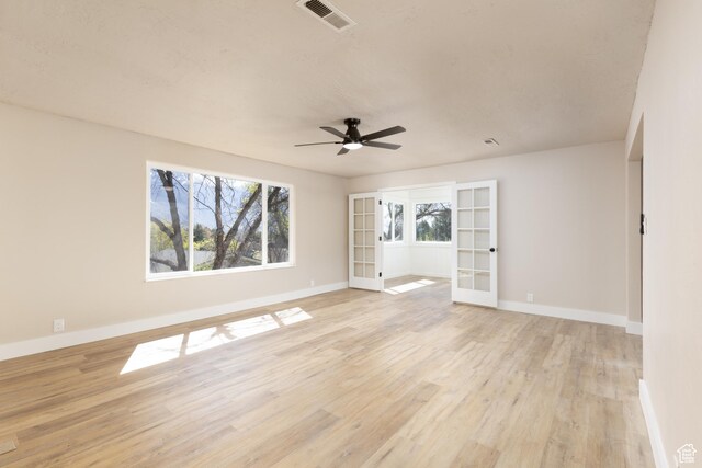 spare room with a ceiling fan, french doors, light wood finished floors, baseboards, and visible vents