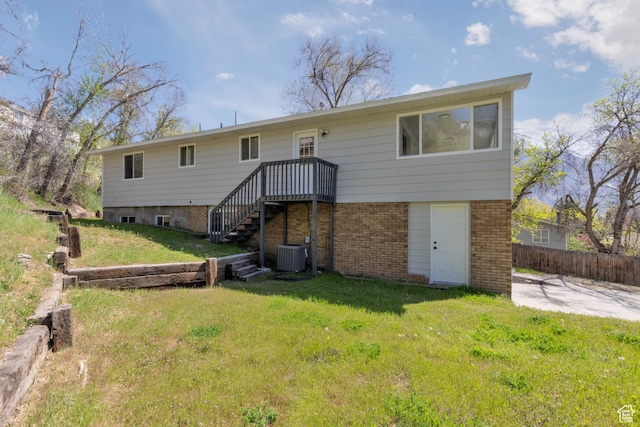 rear view of property with stairs, fence, a yard, central air condition unit, and brick siding
