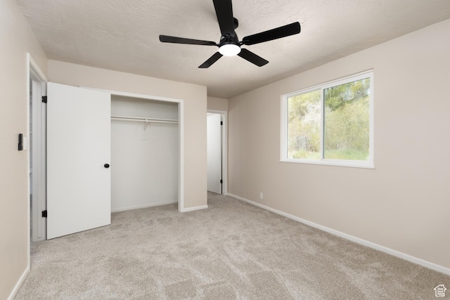 unfurnished bedroom with a textured ceiling, baseboards, a closet, ceiling fan, and carpet floors