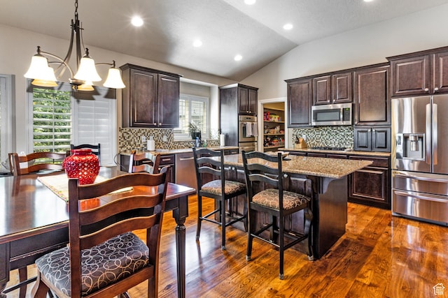 6061 S Bridges Ln, Murray, UT 84121 - kitchen with vaulted ceiling, appliances with stainless steel finishes, dark brown cabinets, and a center island with sink