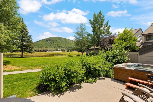 view of patio with a hot tub and a mountain view