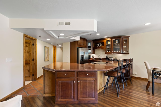 kitchen with visible vents, baseboards, a peninsula, a kitchen bar, and stainless steel refrigerator with ice dispenser