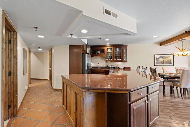 kitchen with recessed lighting, stainless steel fridge with ice dispenser, visible vents, a center island, and glass insert cabinets