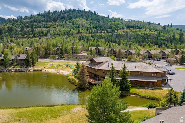 birds eye view of property with a water view and a wooded view
