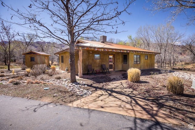 674 E Dragon Fly Trl, Moab, UT 84532 - view of front facade with an outdoor structure, a chimney, metal roof, and a mountain view