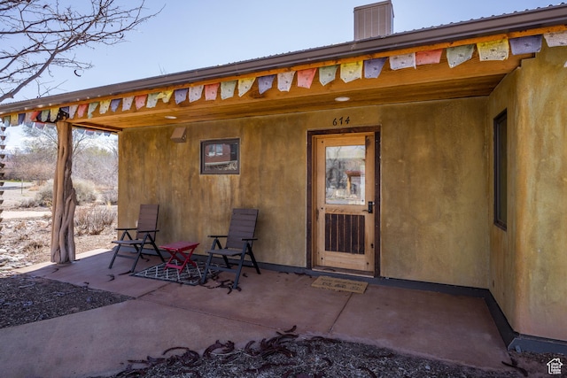 exterior space featuring stucco siding, a chimney, and a patio