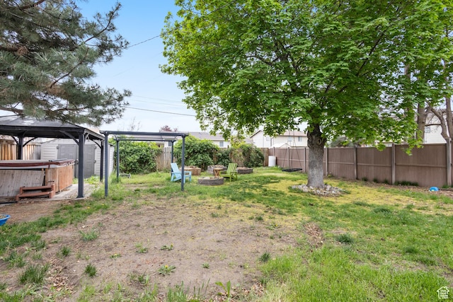 view of yard featuring a fire pit, fence private yard, a gazebo, and a hot tub