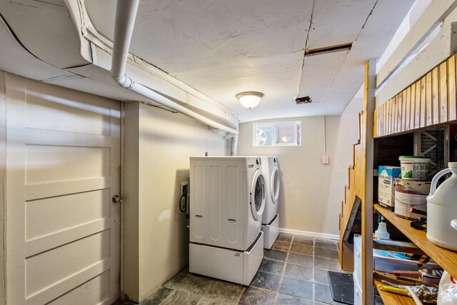 laundry room featuring separate washer and dryer, baseboards, and stone tile flooring