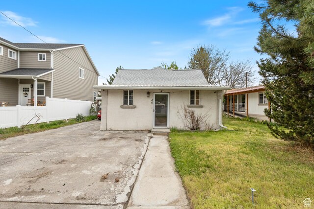 view of front facade featuring fence, a front lawn, and stucco siding