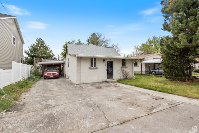 view of front of property with a carport, driveway, fence, a shingled roof, and stucco siding