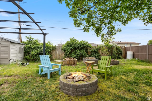 view of yard with a fire pit, a shed, a fenced backyard, and an outdoor structure
