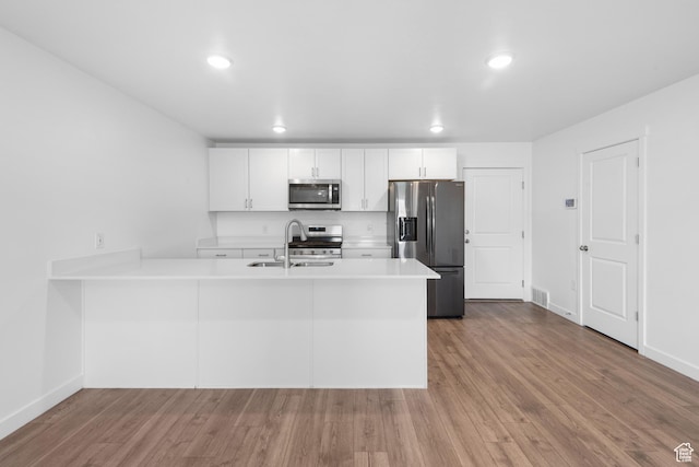 580 Hal St, Stansbury Park, UT 84074 - kitchen featuring recessed lighting, light countertops, wood finished floors, a peninsula, and appliances with stainless steel finishes