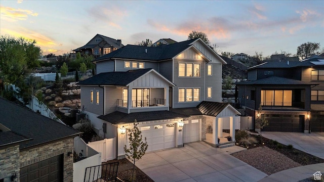 view of front of property with fence, a balcony, concrete driveway, an attached garage, and board and batten siding