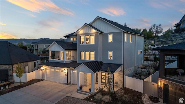 view of front of house featuring board and batten siding, an attached garage, fence, and a gate