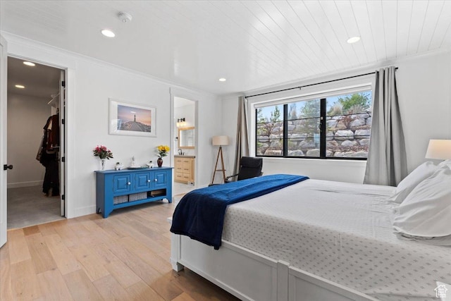 bedroom with a spacious closet, ensuite bath, light wood-style floors, and recessed lighting
