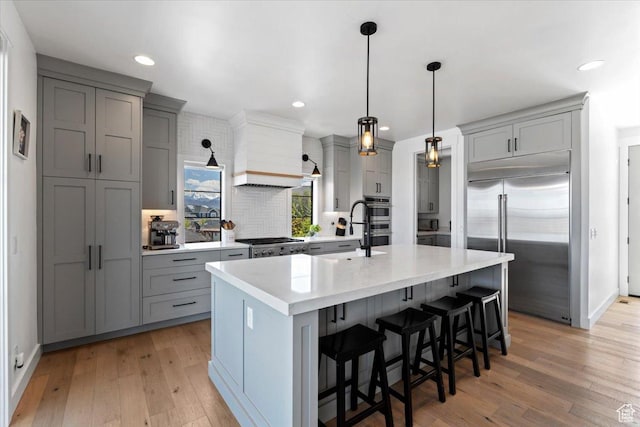 kitchen with gray cabinetry, stainless steel appliances, and light wood-style flooring