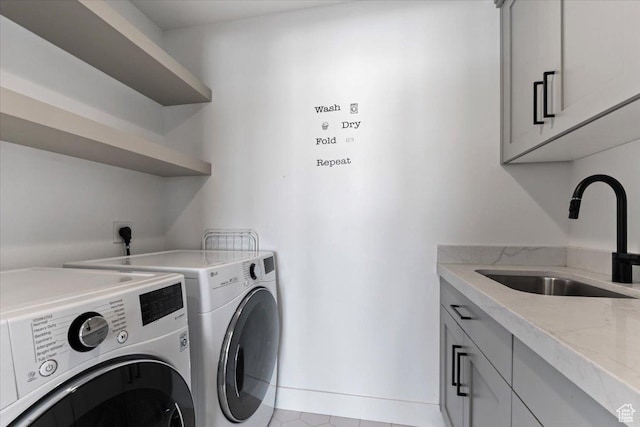 washroom with washing machine and dryer, cabinet space, and a sink