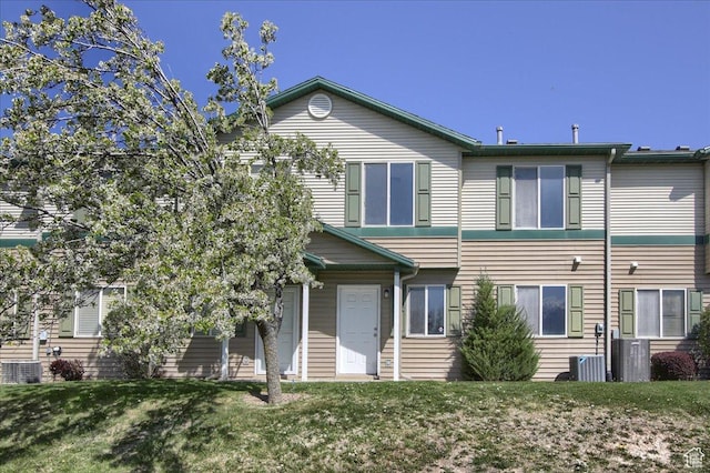 townhome / multi-family property with cooling unit and a front lawn