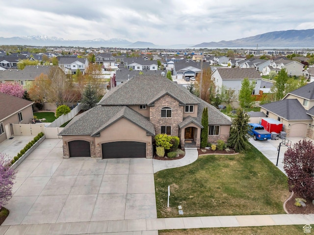 french country inspired facade featuring a garage, driveway, stone siding, a front yard, and a residential view