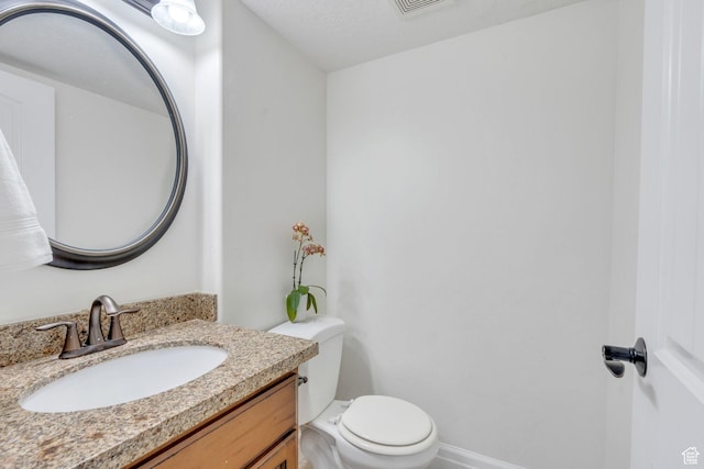 half bath featuring toilet, vanity, and baseboards