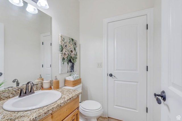 half bath featuring vanity and toilet