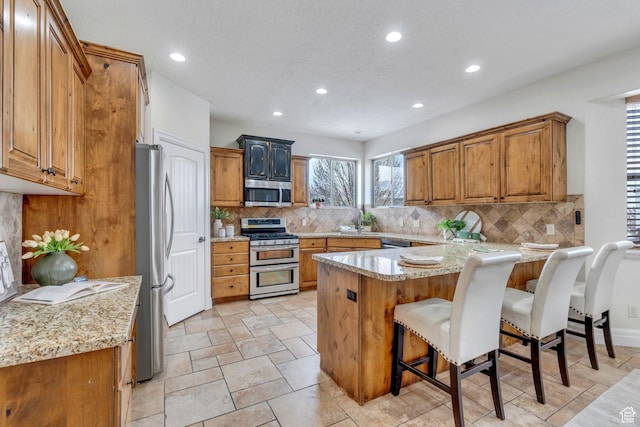 kitchen with a kitchen bar, backsplash, stainless steel appliances, and recessed lighting