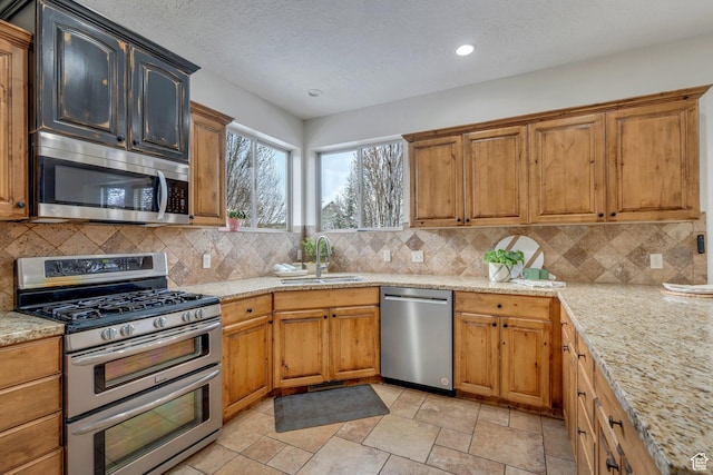 kitchen featuring tasteful backsplash, a textured ceiling, stainless steel appliances, and a sink