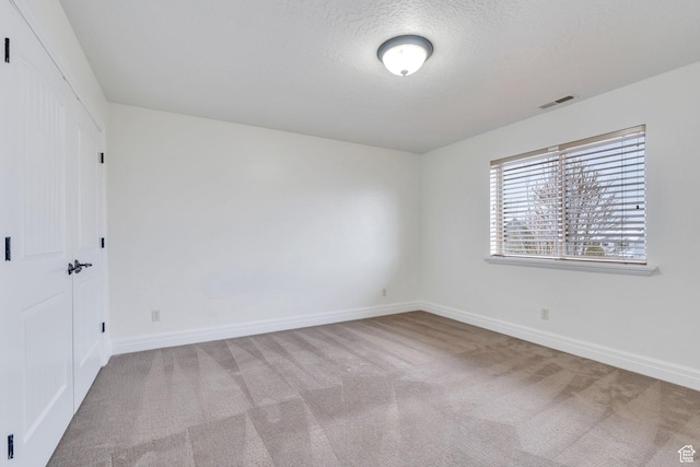 unfurnished bedroom with baseboards, visible vents, carpet, and a textured ceiling
