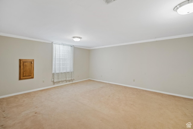 empty room featuring light carpet, crown molding, and baseboards