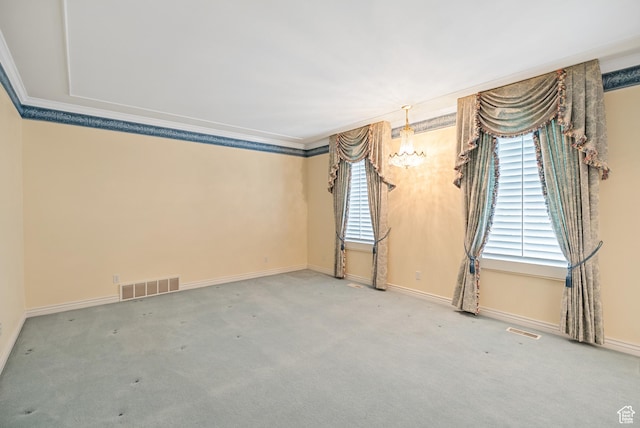 carpeted spare room featuring visible vents, a wealth of natural light, and crown molding