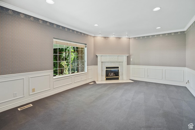 unfurnished living room featuring a premium fireplace, a wainscoted wall, carpet, visible vents, and recessed lighting