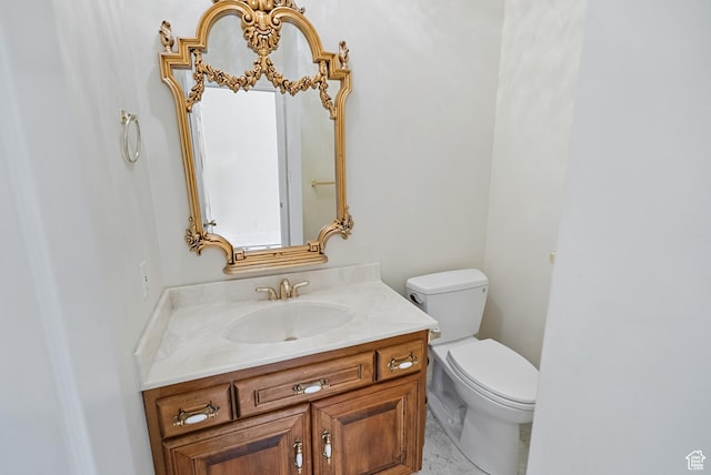 bathroom with marble finish floor, toilet, and vanity