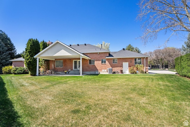 back of house featuring a lawn, brick siding, a patio area, and french doors