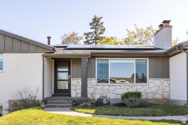 1045 E Claremont Dr S, Bountiful, UT 84010 - doorway to property with a chimney, roof mounted solar panels, stone siding, and board and batten siding