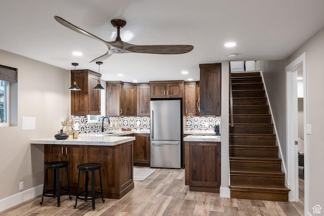 1045 E Claremont Dr S, Bountiful, UT 84010 - kitchen featuring a peninsula, light wood-style flooring, tasteful backsplash, freestanding refrigerator, and a ceiling fan