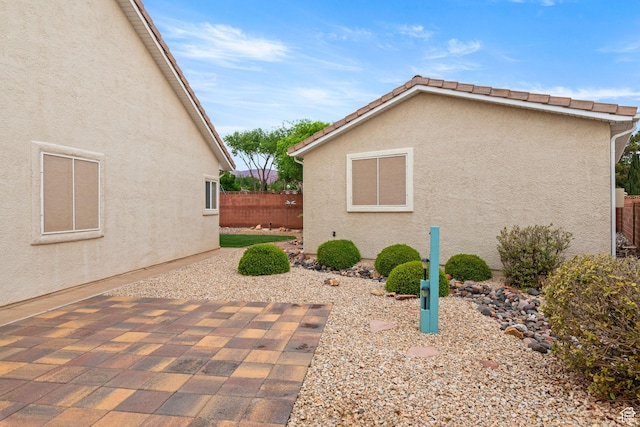 view of property exterior featuring fence, a patio area, and stucco siding