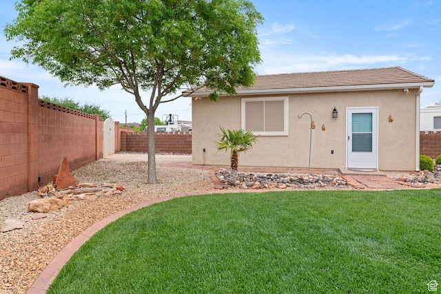 rear view of house with a lawn, a fenced backyard, a tiled roof, and stucco siding