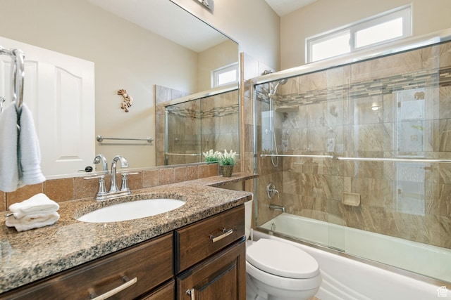 bathroom featuring plenty of natural light, toilet, vanity, and enclosed tub / shower combo