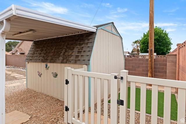 view of property exterior featuring a fenced backyard, an outbuilding, and a shingled roof