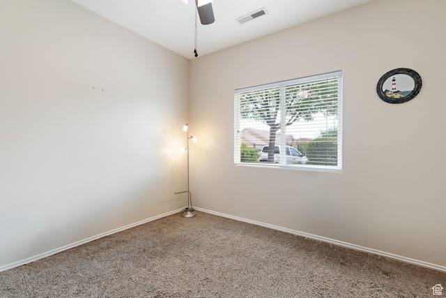 carpeted spare room with visible vents, baseboards, and ceiling fan